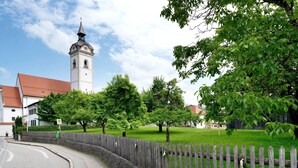 A street with a church tower, a wooden fence, and trees. - Apartment 'Komfort  Römersberger - 1' with Wi-Fi (Vogtareuth)