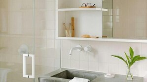 A modern bathroom with a glass shower enclosure, a concrete sink, and a mirrored wall above the sink. - The Industrialist Belvilla District 6 Formerly Sonder (Brooklyn)