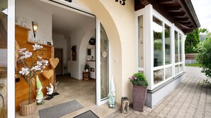 A building entrance with a number 13, a door, a small table with a plant, and a decorative gnome figure. - Holiday Apartment 'Komfort Römersberger - 6' with Private Terrace, Private Garden and Wi-Fi (Vogtareuth)