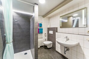 A bathroom with a shower, toilet, sink, and a mirror.
