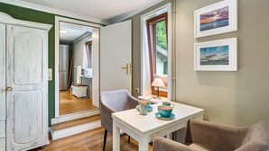 Una habitación con una mesa de comedor, sillas, un armario y dos cuadros colgados en la pared.
