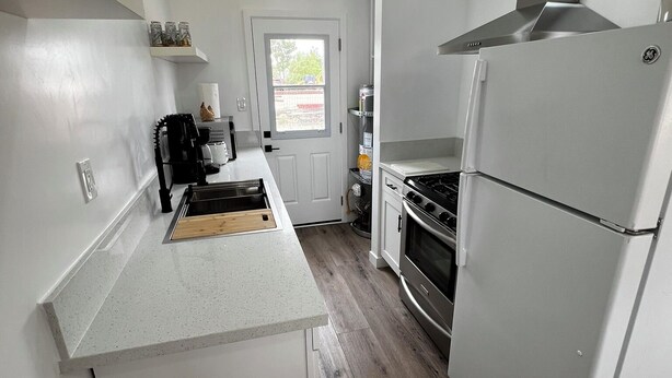 A compact kitchen with white cabinetry, a stainless steel refrigerator, a stove, and a microwave. - Updated 1BR w/ Kitchen, Fast WiFi + Highway Access Near Carrizo Plain (Cuyama)