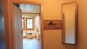Un pasillo con una puerta de madera, un espejo y un adorno en la pared.