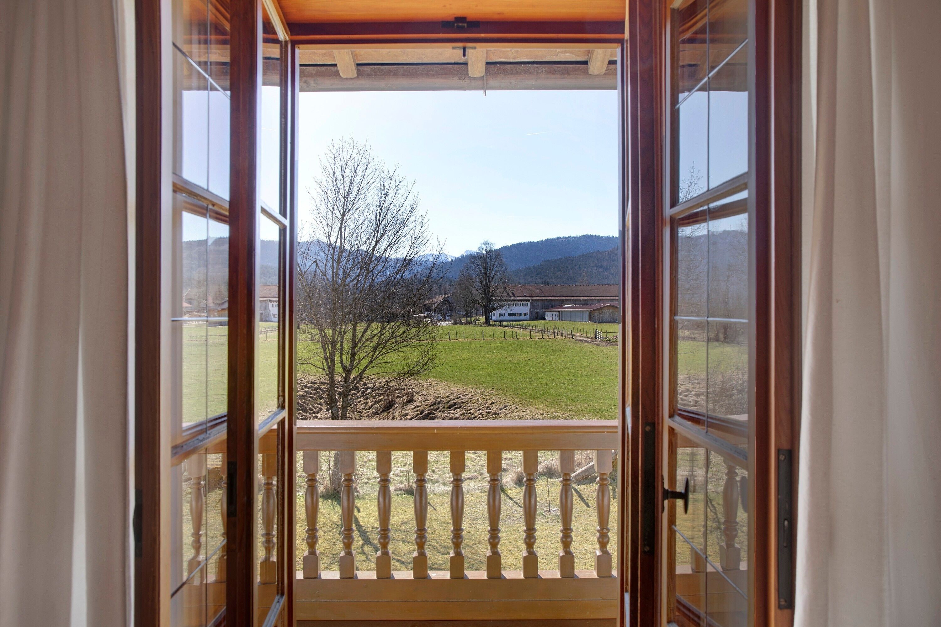 Eine geöffnete Tür mit Blick auf eine Wiese und Gebäude in der Ferne.