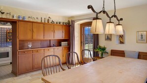 Un comedor con mesa y sillas de madera, una cocina con armarios de madera y una lámpara colgante.