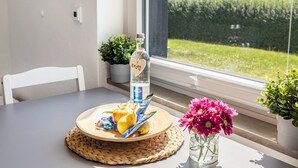 A table with a bottle of water, a woven placemat, a vase with flowers, and a window with a view of greenery. - Panoramanest Sauerland with Sun Terrace, Near Sorpesee Lake and Hiking Trails (Balve)