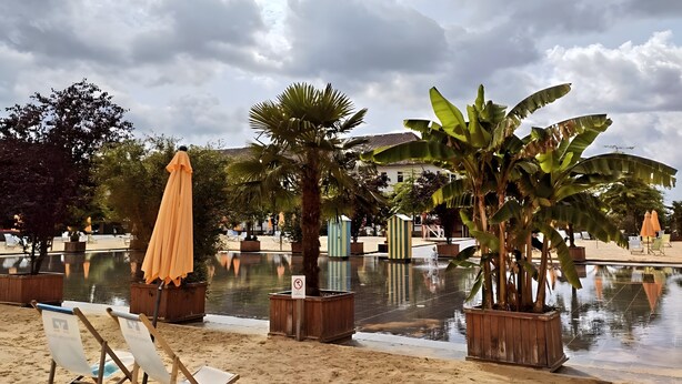 A beachside area with lounge chairs, umbrellas, and a pool reflecting the sky. - Panoramanest Sauerland with Sun Terrace, Near Sorpesee Lake and Hiking Trails (Balve)