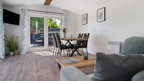Un salón moderno con una mesa de comedor de madera, un sofá gris y un televisor montado en la pared.