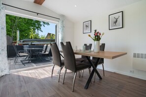 Uma sala de jantar com uma mesa de madeira, quatro cadeiras e duas fotos emolduradas na parede.