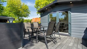 Una terraza con mobiliario exterior, una puerta de cristal y vistas del entorno.
