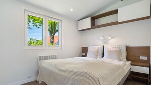 Un dormitorio con cama, ventana, estante empotrado e iluminación fijada a la pared.