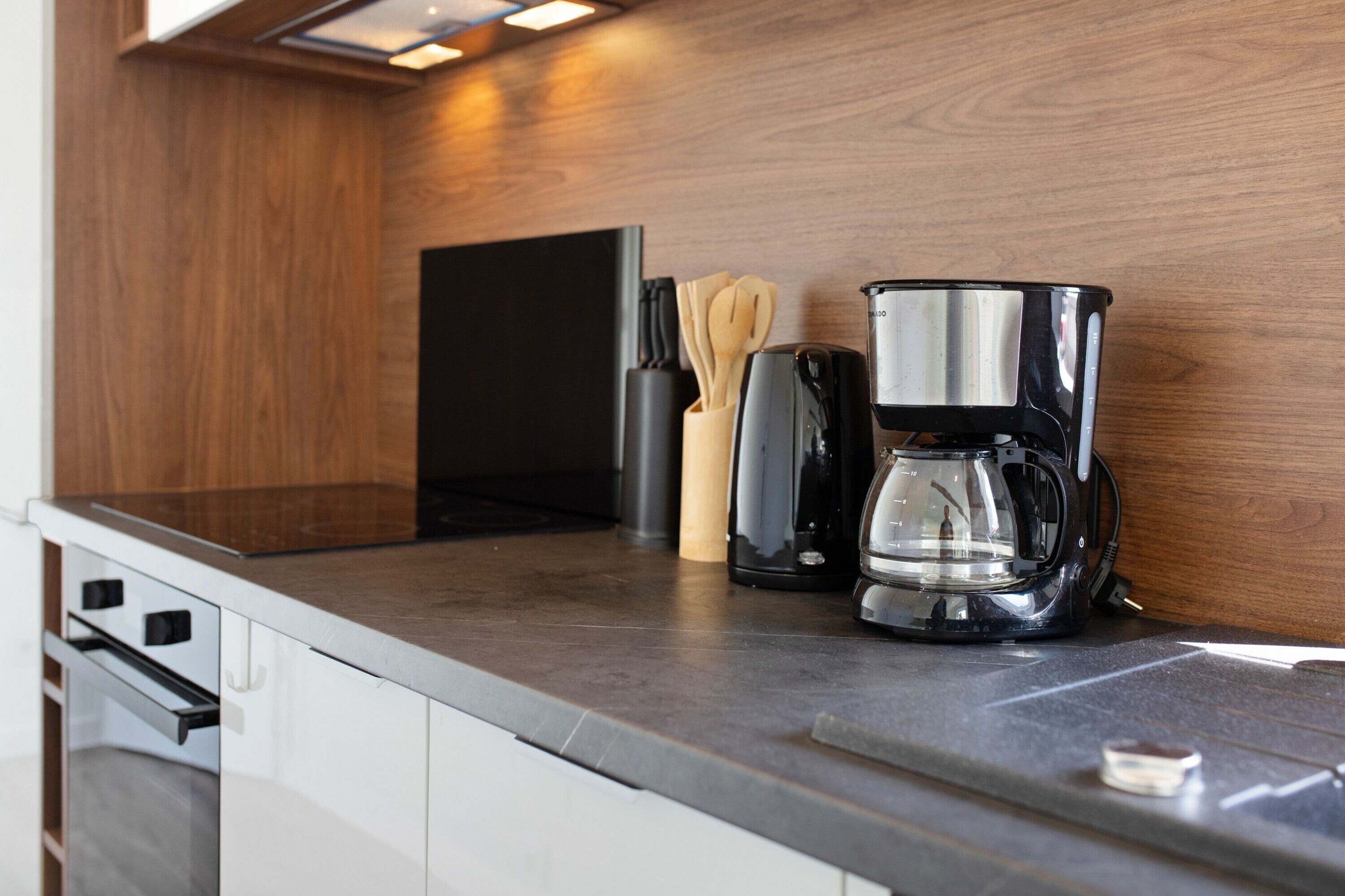 Una cucina con una macchina da caffè, utensili e un elettrodomestico nero sul piano di lavoro.
