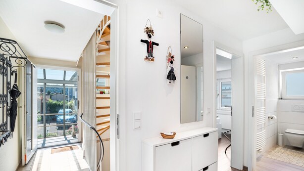 A modern interior with a staircase, white walls, and a large mirror.