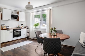 A modern kitchen with white cabinets, a built-in oven, and a dining area with a round table and chairs. - Apartment 'Albi' with Mountain View, Shared Terrace and Wi-Fi (Waldkirch)