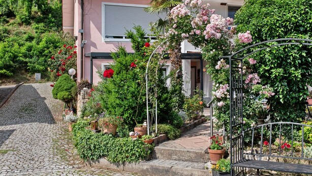 Una casa con jardín, un camino de piedra y una verja de metal.