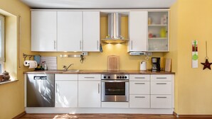Una cocina compacta con armarios blancos, horno de acero inoxidable y cafetera.