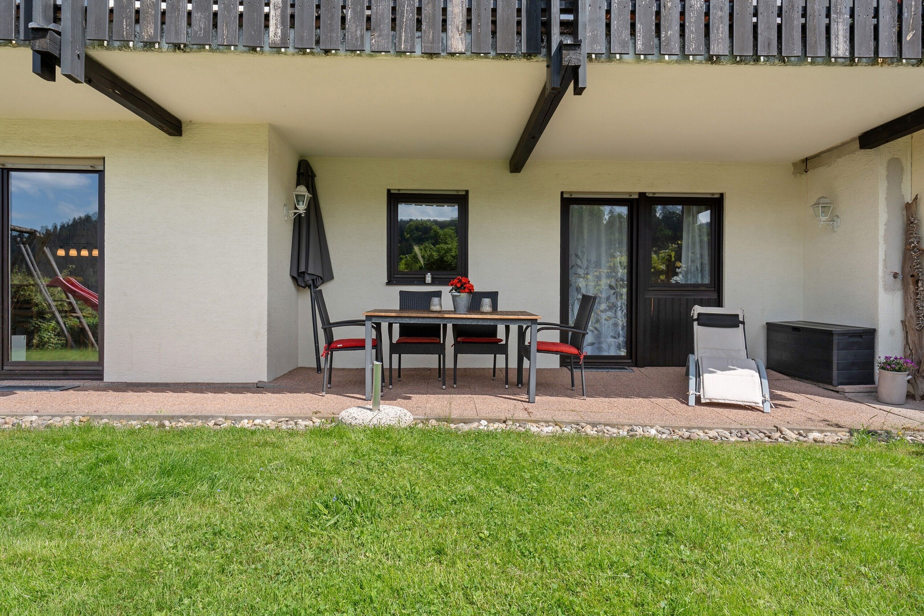 Een terras met een tafel en stoelen, een schuifdeur en een klein zitgedeelte buiten.
