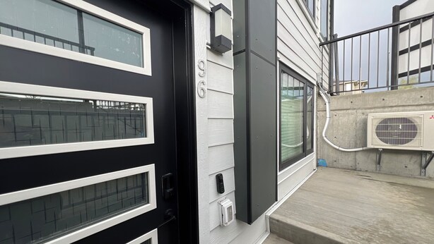 A modern building with a black door, white-framed windows, and a concrete staircase. - Cozy 2 bedrooms Suite Near Calgary Airport ✈️ | Air conditioning Sleeps 6 (Calgary)