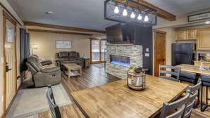 Un amplio salón con chimenea de piedra, una mesa de comedor y asientos cómodos.