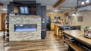 Una cocina moderna con chimenea de piedra, suelo de madera y una zona de comedor con banco.