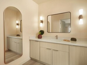 Un baño moderno con tocador doble, un espejo grande e iluminación en la pared.