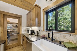 A modern kitchen with wooden cabinets, a large window, and a built-in sink.