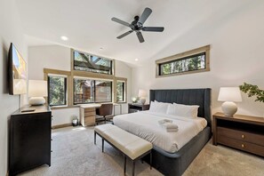 A bedroom with a bed, desk, chair, and a ceiling fan.