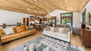 A spacious living area with a high ceiling, wooden beams, a kitchen with a central island, and large windows. - Tahoe Forest Lodge: A/C, Hot Tub, Pool Table (South Lake Tahoe)
