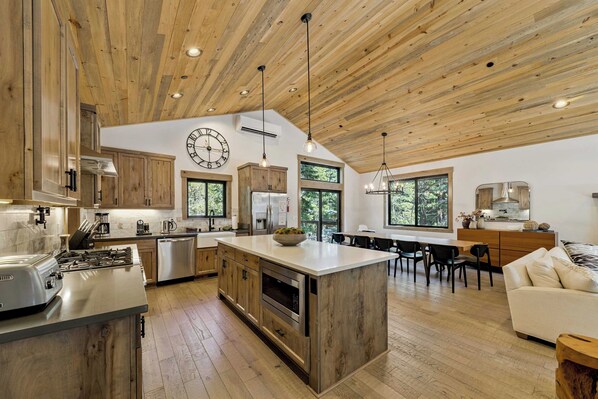 A spacious kitchen with wooden cabinets, a central island, and a dining area with a view of the outdoors.