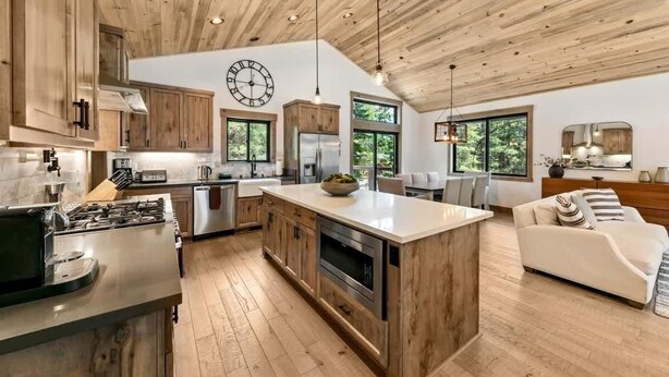 A spacious kitchen with wooden cabinets, a large island, and a dining area with a sofa. - Tahoe Forest Lodge: A/C, Hot Tub, Pool Table (South Lake Tahoe)