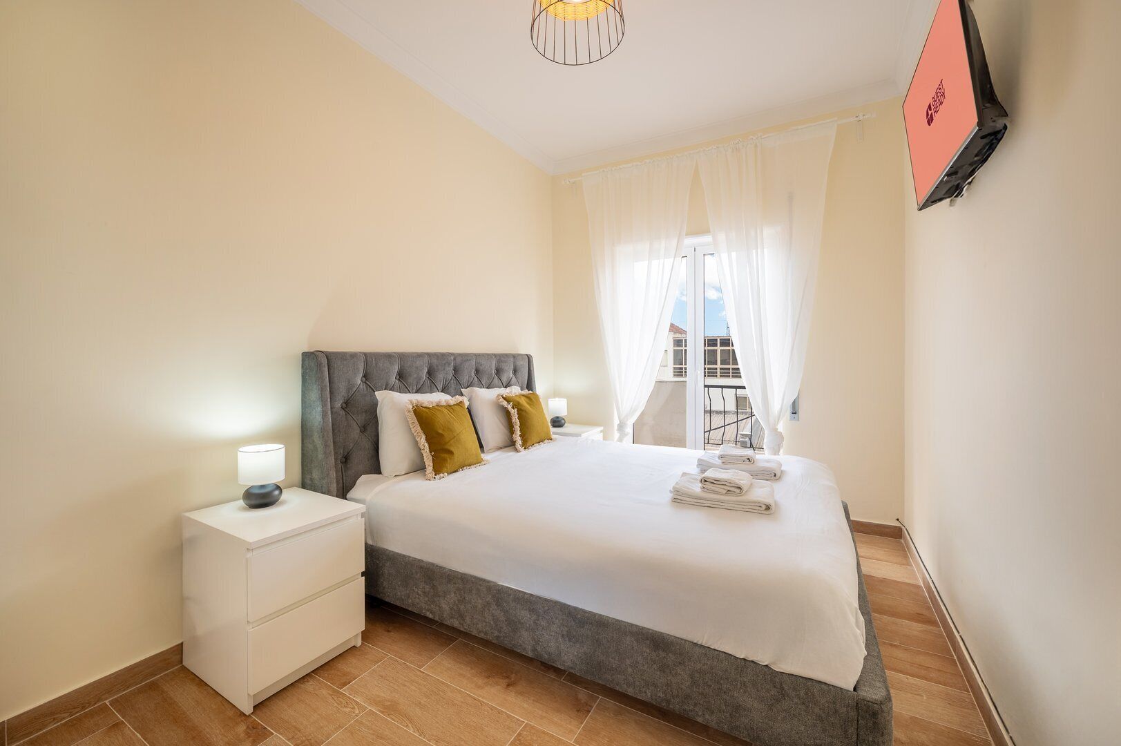A bedroom with a bed, nightstand, and a TV mounted on the wall.