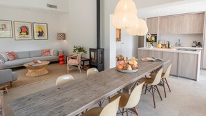 A modern living room with a wooden dining table, a sofa, and a kitchen area with a stove. - Luxury villa with A/C and a heated private pool (La Croix-Valmer)