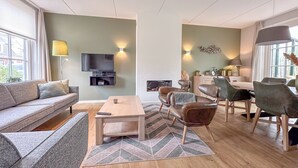 Un salon moderne comprenant un canapé, une table basse et un coin repas avec des chaises.
