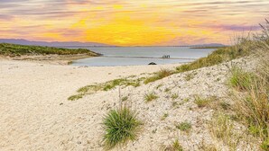 Une plage offrant une vue sur le coucher de soleil, un sol sablonneux et un petit quai.