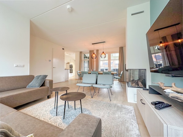 A modern living room with a sofa, two round tables, and a dining area with chairs.