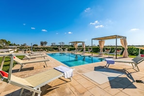 Ein Schwimmbad mit Liegestühlen und einer Pergola.