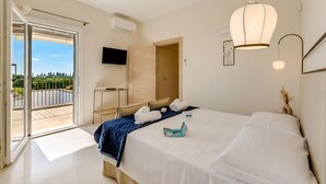 A hotel room with a bed, a desk, a TV, and a balcony with a view. - Villa Elysium for 10 With Pool Near Gallipoli (Alezio)