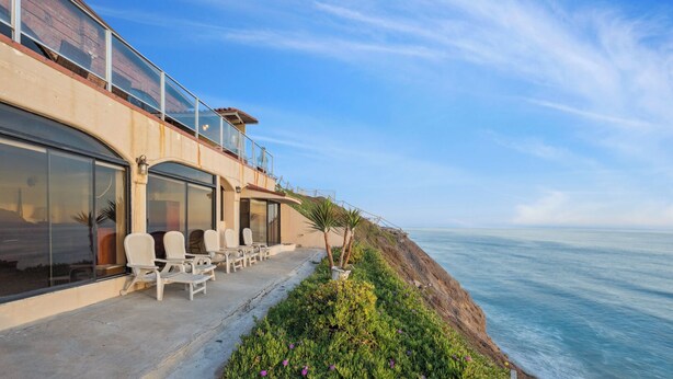 Ein Hotel am Meer mit einer Terrasse mit Blick auf den Ozean, inklusive Sitzgelegenheiten im Freien und Ausblick auf die Küste.