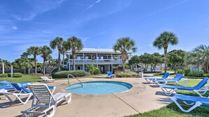 A pool area with lounge chairs and a building in the background. - Oceanfront Condo in Harbor Island Community! (St Helena Island)