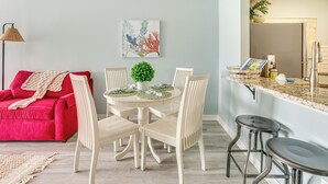 A dining area with a round table, white chairs, a small potted plant, and a red couch. - Oceanfront Condo in Harbor Island Community! (St Helena Island)