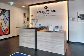 A reception desk with a sign reading "CANDLEWOOD SUITES BY IHG" and a framed artwork on the wall.