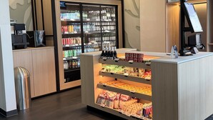 A self-service beverage station with a refrigerated display and a snack counter. - Candlewood Suites BERLIN CHARLOTTENBURG by IHG (Berlin)