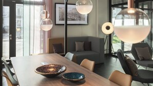 A modern dining area with a wooden table, two decorative bowls, and contemporary pendant lights. - Candlewood Suites BERLIN CHARLOTTENBURG by IHG (Berlin)