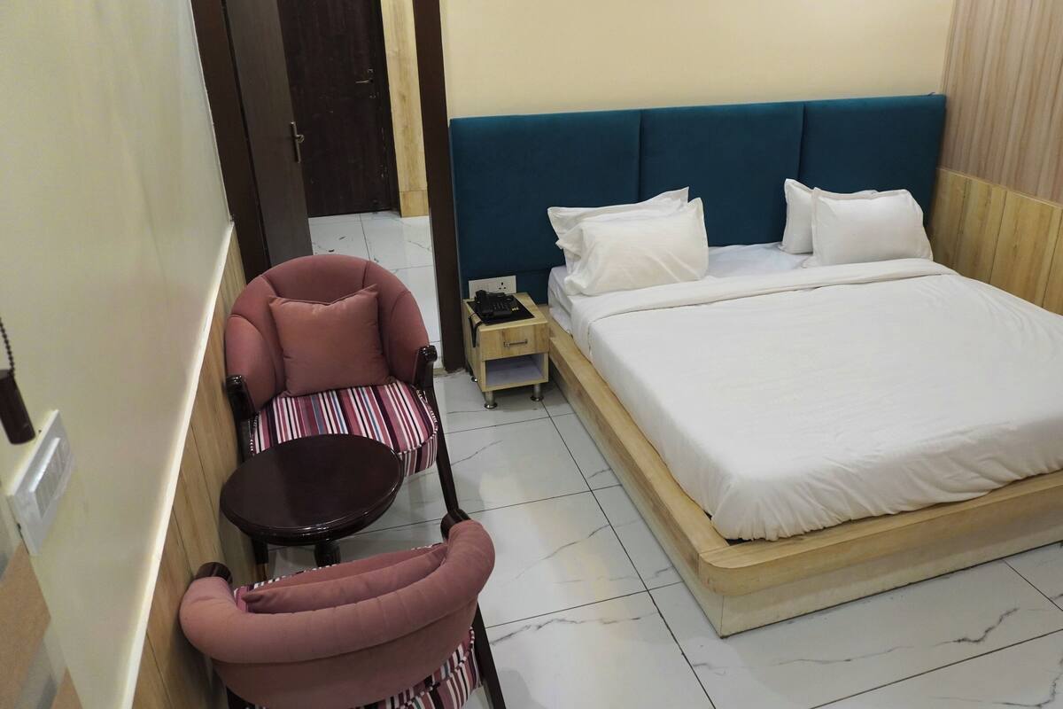 A hotel room with a bed, a chair, a small table, and a nightstand.