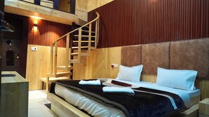 Ein Zimmer mit Holzboden, einem Bett, einer Treppe und einer roten Wand.