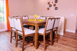 A dining room with a wooden table and six chairs, a vase with yellow flowers, and decorative wall mirrors.