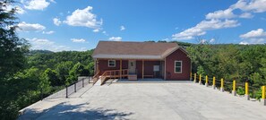 A red building with a porch, a staircase, and a fenced area.