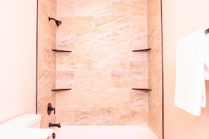 A bathroom with a shower area, a toilet, and a towel hanging on the wall.