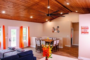 A room with a ceiling fan, a dining table with chairs, a sofa, and a vase with flowers. - Rustic Haven- Heated Pool Open, Hot tub, EV, Spa, Wheel Chair & Privacy (Branson)