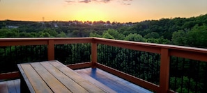A wooden deck with a railing overlooking a forested area during sunset. - Rustic Haven- Heated Pool Open, Hot tub, EV, Spa, Wheel Chair & Privacy (Branson)